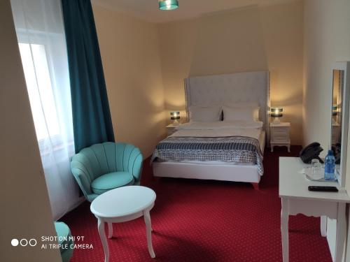 a bedroom with a bed and a chair and a table at Hotel i Restauracja Admirał in Legnica