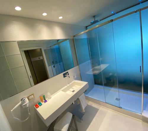 a bathroom with a sink and a large mirror at Devero Hotel & Spa, BW Signature Collection in Cavenago di Brianza