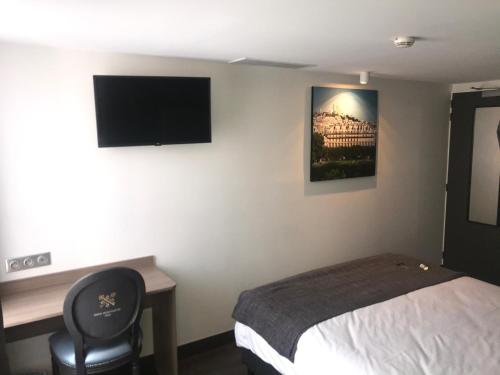 a bedroom with a bed and a desk and a television at Hotel de Paris Montmartre in Paris