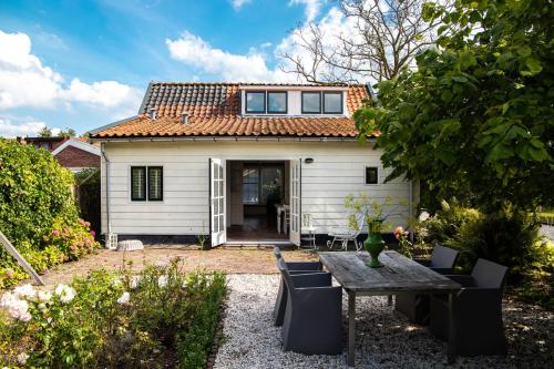 a small white house with a table and chairs at Gastenverblijf KortVertoef in Kortenhoef