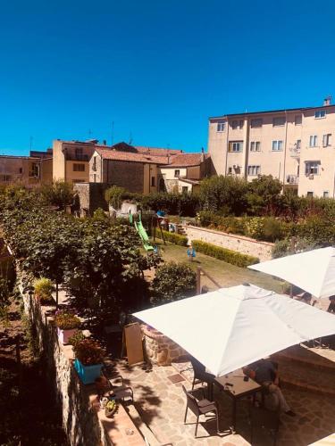 eine Terrasse mit Tischen, weißen Sonnenschirmen und Gebäuden in der Unterkunft Delizie tra i campanili in Gioi