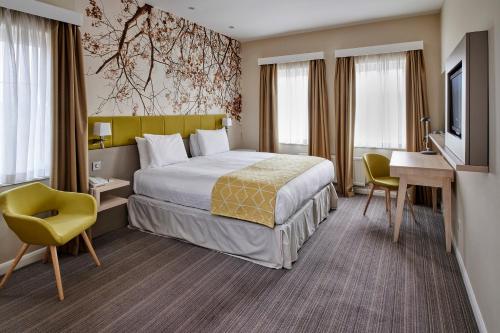 Habitación de hotel con cama, escritorio y TV. en Holiday Inn Corby Kettering A43, an IHG Hotel en Corby