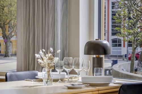 a table with wine glasses and a lamp on it at Hotel Svendborg in Svendborg