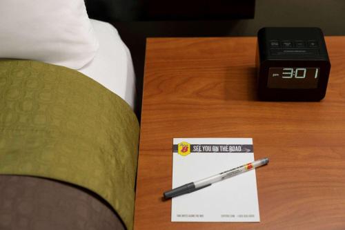 a pen on a table next to a alarm clock at Super 8 by Wyndham West Greenwich/Providence in West Greenwich