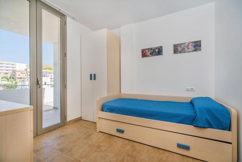 a bedroom with a bed with blue sheets and a window at MOLINS 3 in Cala de Sant Vicenc