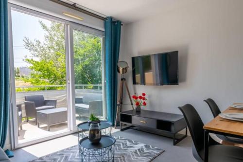 un salon avec une télévision, une table et des chaises dans l'établissement APPARTEMENT LUMINEUX ET AGRÉABLE - PROCHE HYPER CENTRE AVIGNON - WiFI GRATUIT, à Avignon