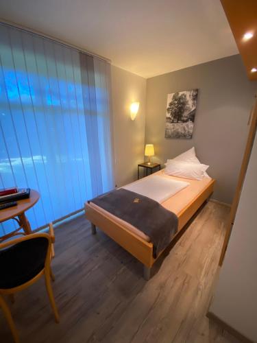 a bedroom with a bed and a desk and a window at Taranga Tagungszentrum und Hotel in Waffensen