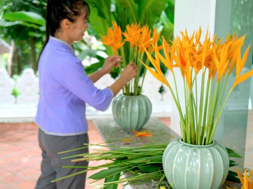 a woman arranging flowers in vases on a table at MonPanaNont Wellness Resort & Spa in Mae Taeng