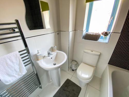 a white bathroom with a toilet and a sink at Contractor Accommodation Specialist, 3 bedroom house with FREE Parking, Wifi & Netflix! in Milton Keynes