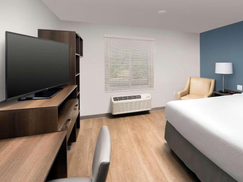 a hotel room with a bed and a flat screen tv at WoodSpring Suites Albuquerque in Albuquerque
