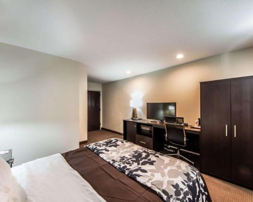 a bedroom with a bed and a desk with a computer at Sleep Inn & Suites Guthrie - Edmond North in Guthrie