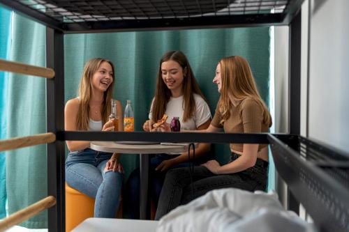 three girls sitting around a table in a room at a&o München Laim in Munich