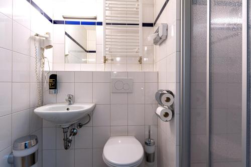 a white bathroom with a toilet and a sink at a&o München Laim in Munich