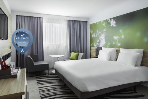 
a bedroom with a large bed and a large window at Novotel Paris Charles de Gaulle Airport in Roissy-en-France
