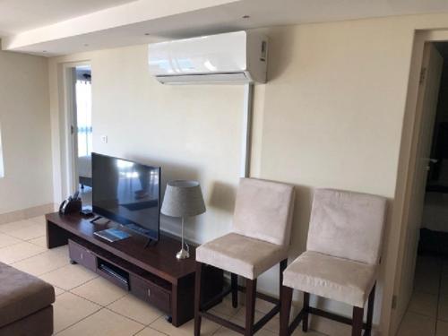 a living room with a television and two chairs at Nautica 501 in Mossel Bay