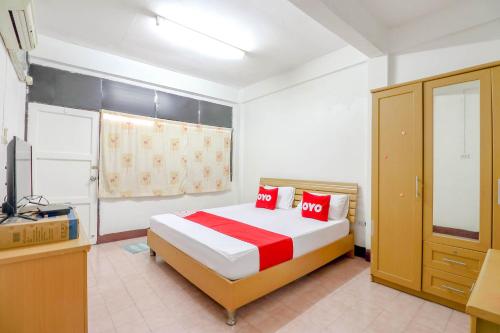um quarto com uma cama com almofadas vermelhas e uma televisão em OYO 525 MRT Phetkasem 48-1 Place em Bangkok