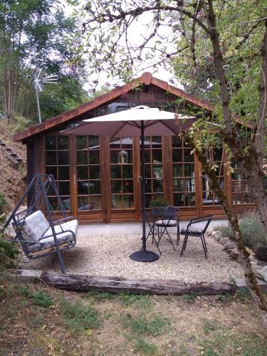 a gazebo with an umbrella and two chairs and a swing at Dependance du Moulin Galuzot in Saint-Vallier