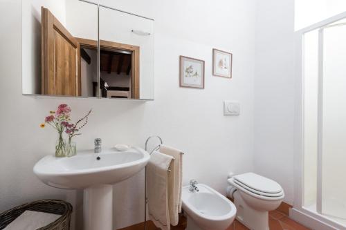 a white bathroom with a sink and a toilet at Casa Dovi in Rosennano