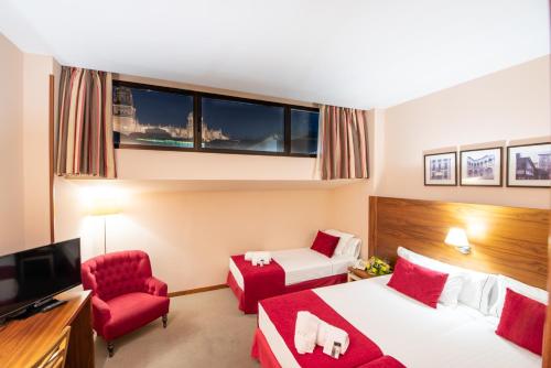 a hotel room with two beds and a red chair at Hospedium Hotel Casino Del Tormes in Salamanca