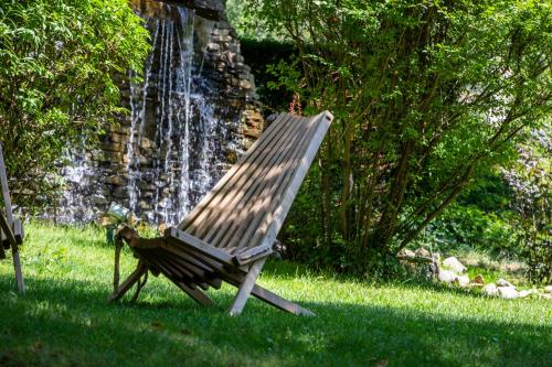 a wooden bench sitting in the grass in front of a waterfall at Caro Hotel in Bucharest