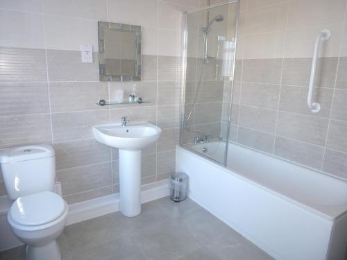 a bathroom with a toilet and a sink and a bath tub at Orrell Park Hotel in Liverpool