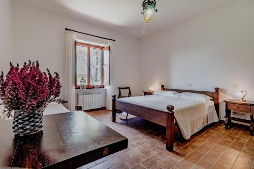 Beautiful 2-storey villa in Todi (room for 18) في تودي: غرفة نوم بسرير و إناء من الزهور