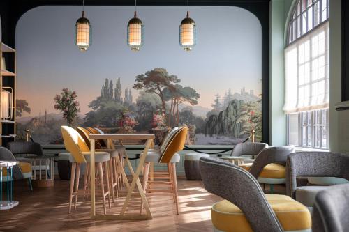 a restaurant with chairs and a table and a mural at Grand Hôtel Bristol in Colmar