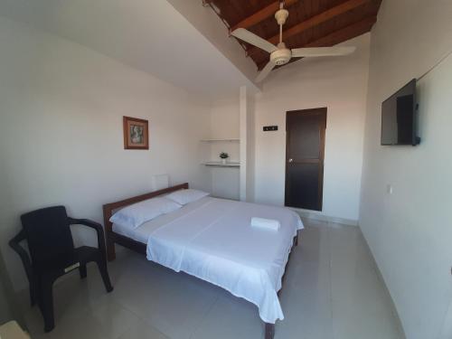 ein weißes Schlafzimmer mit einem Bett und einem Stuhl in der Unterkunft Hotel Anita in Puerto Berrío