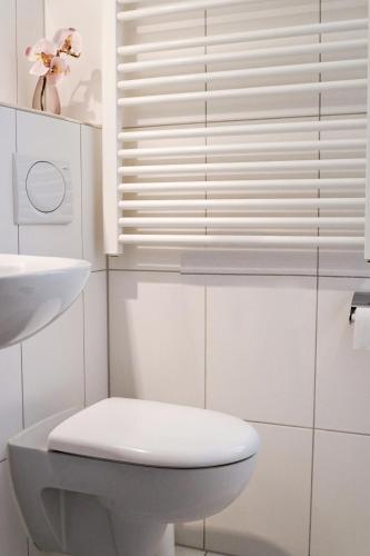 a white bathroom with a toilet and a sink at Hotel im Kupferkessel in Cologne