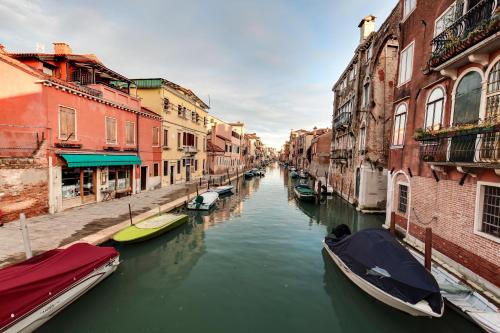 un canal en una ciudad con barcos en el agua en Cannaregio suite with garden en Venecia
