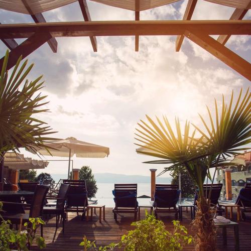 Un patio con sillas y mesas y vista al mar. en Villa Mina, en Ohrid