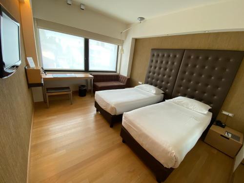 a hotel room with two beds and a desk at Devero Hotel & Spa, BW Signature Collection in Cavenago di Brianza