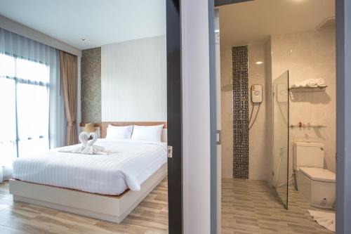 a bedroom with a white bed and a bathroom at Eireann Boutique Hotel in Prakhon Chai