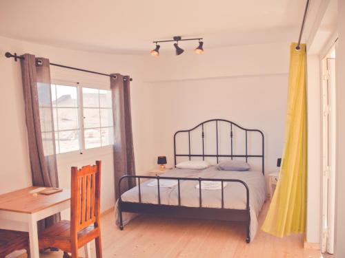 a bedroom with a bed and a table and a desk at Gartenappartement - Tierra - Surf & Yoga Villa in La Pared