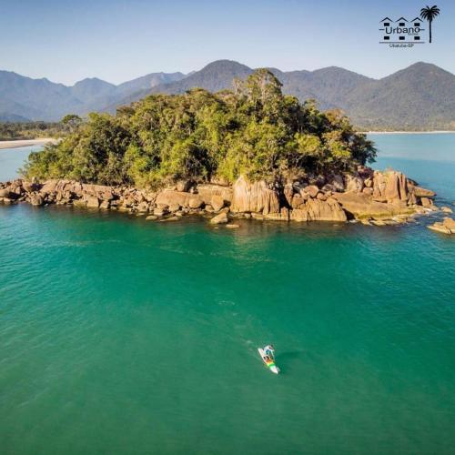 a person in a boat in the water near an island at Urbano Suítes in Ubatuba