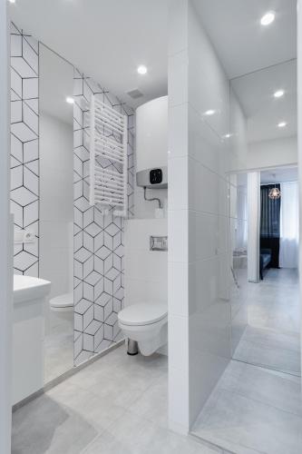 a white bathroom with a toilet and a sink at Crystal Apartment Katowice III in Katowice
