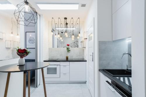 Una cocina con gabinetes blancos y una mesa. en Crystal Apartment Katowice III, en Katowice