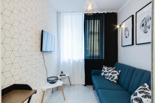 Una sala de estar con un sofá azul y una mesa. en Crystal Apartment Katowice III, en Katowice