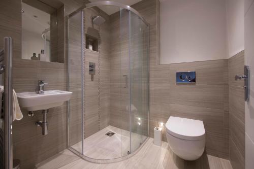 a bathroom with a shower and a toilet and a sink at ChocoLets - The Foss Suite in York