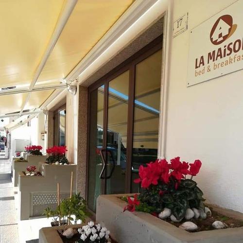 a building with red flowers in front of a store at B&B la Maison in Sammichele di Bari