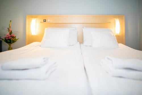 a white bed with two pillows and a vase of flowers at Hotel Uusikuu in Mikkeli