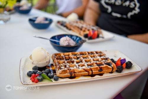 a plate of waffles and berries on a table at Lavender Inn Guest House in Viešvėnai
