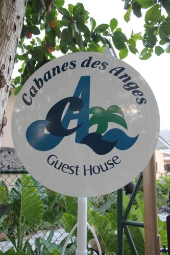 a sign for a guest house in front of a fence at Cabanes Des Anges in La Digue