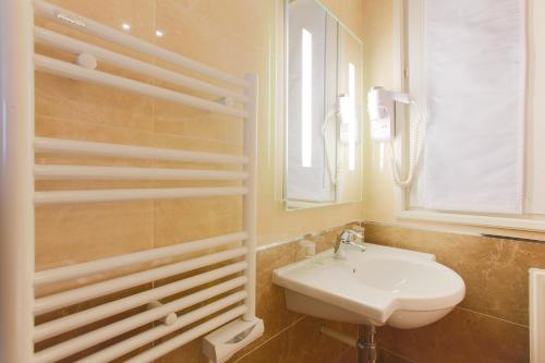 a white bathroom with a sink and a mirror at Hotel Bellevue Saint-Lazare in Paris