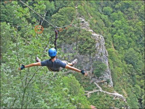 a person in a helmet hanging from a zip line at Hotel Puente Vidosa in Amieva