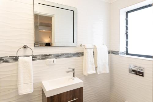 bagno bianco con lavandino e specchio di Grand House Lodge And SPA Jeffreys Bay a Jeffreys Bay