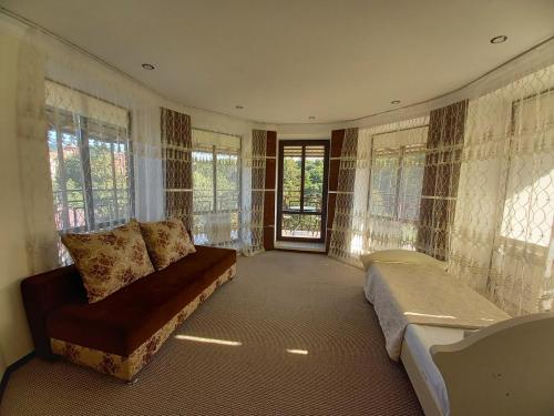 a living room with a couch and windows at Guest House Stary Zamok in Kislovodsk