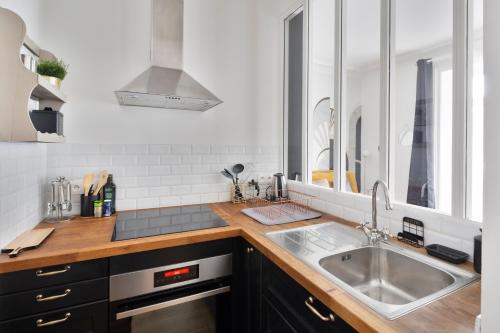 uma cozinha com um lavatório de aço inoxidável e um balcão em Le Contour Saint-Aubin - Inspiration Art Déco en cœur de Ville em Rennes