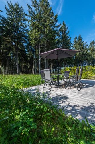 a group of chairs and an umbrella on a patio at Hotel Královka in Bedřichov