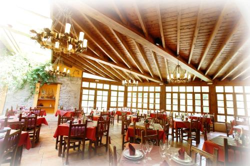 una sala da pranzo con tavoli, sedie e lampadari a braccio di Hotel Puente Vidosa ad Amieva